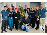 Mira Mamtani, standing on the right side of a Christmas tree, poses with ten residents and physicians in the Emergency Department